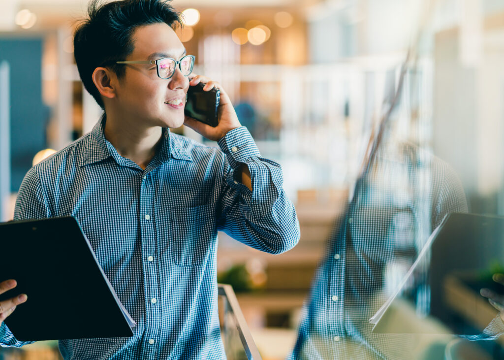 Man talking on his phone and holding his laptop