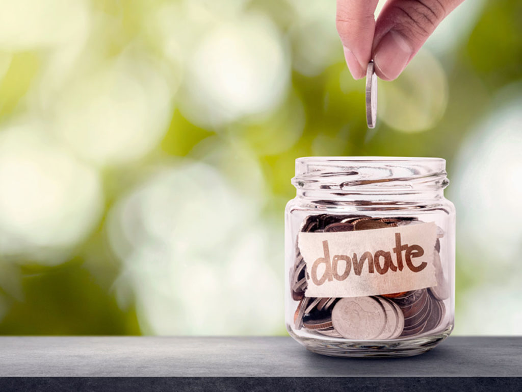 Person dropping a coin into a donation jar