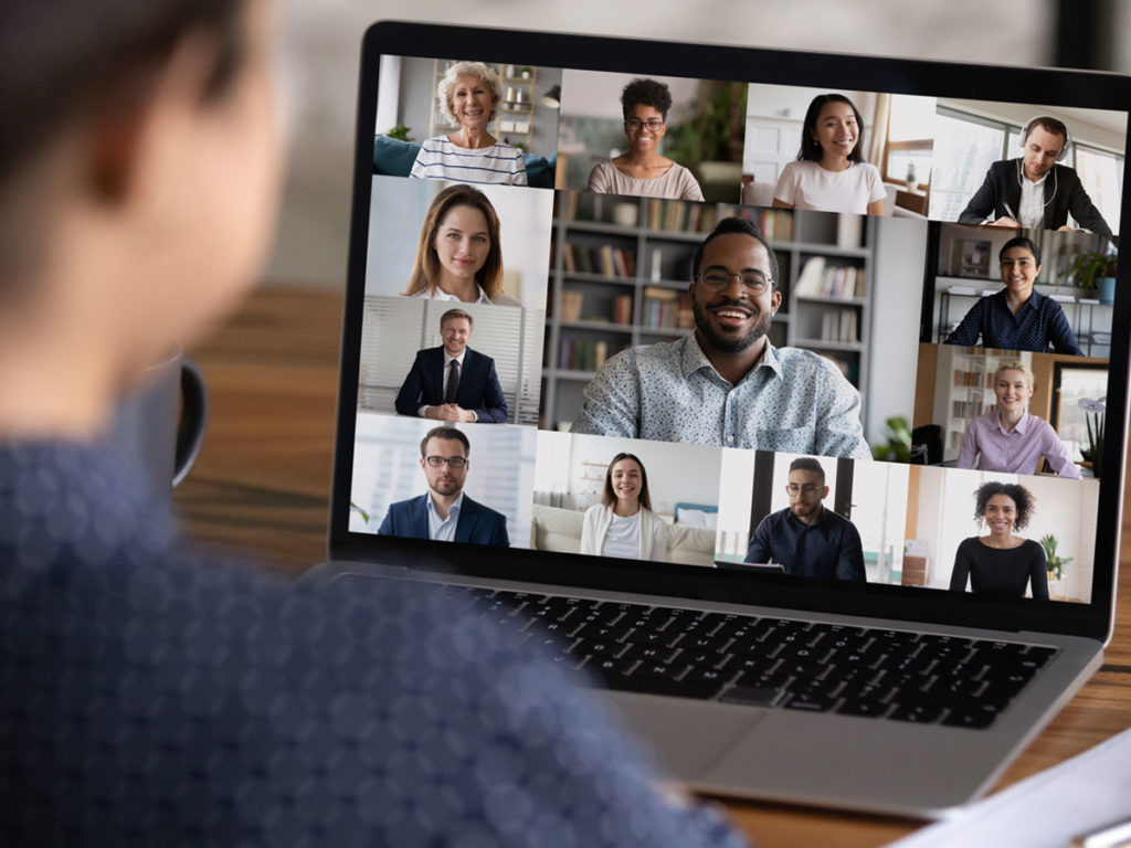 Man watching a laptop showing 13 colleagues on a zoom call