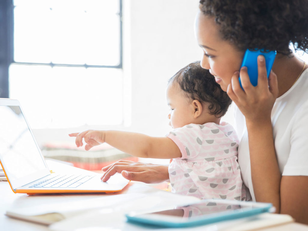 Mom on phone and laptop with baby on lap