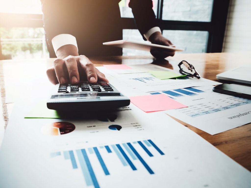 office profiessional using a calculator with graphs on a table