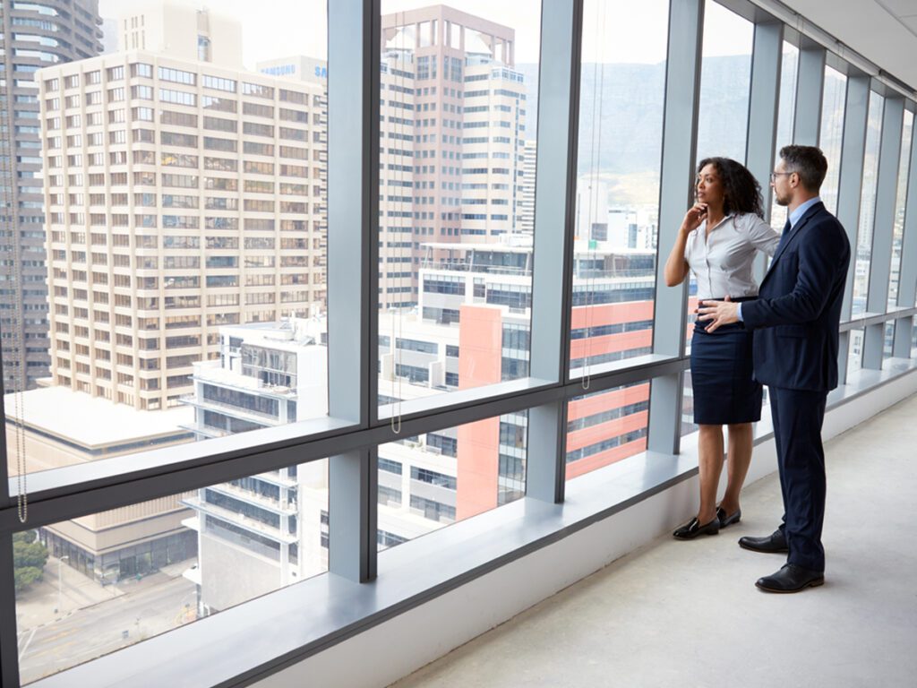 two business people looking out a high rise window